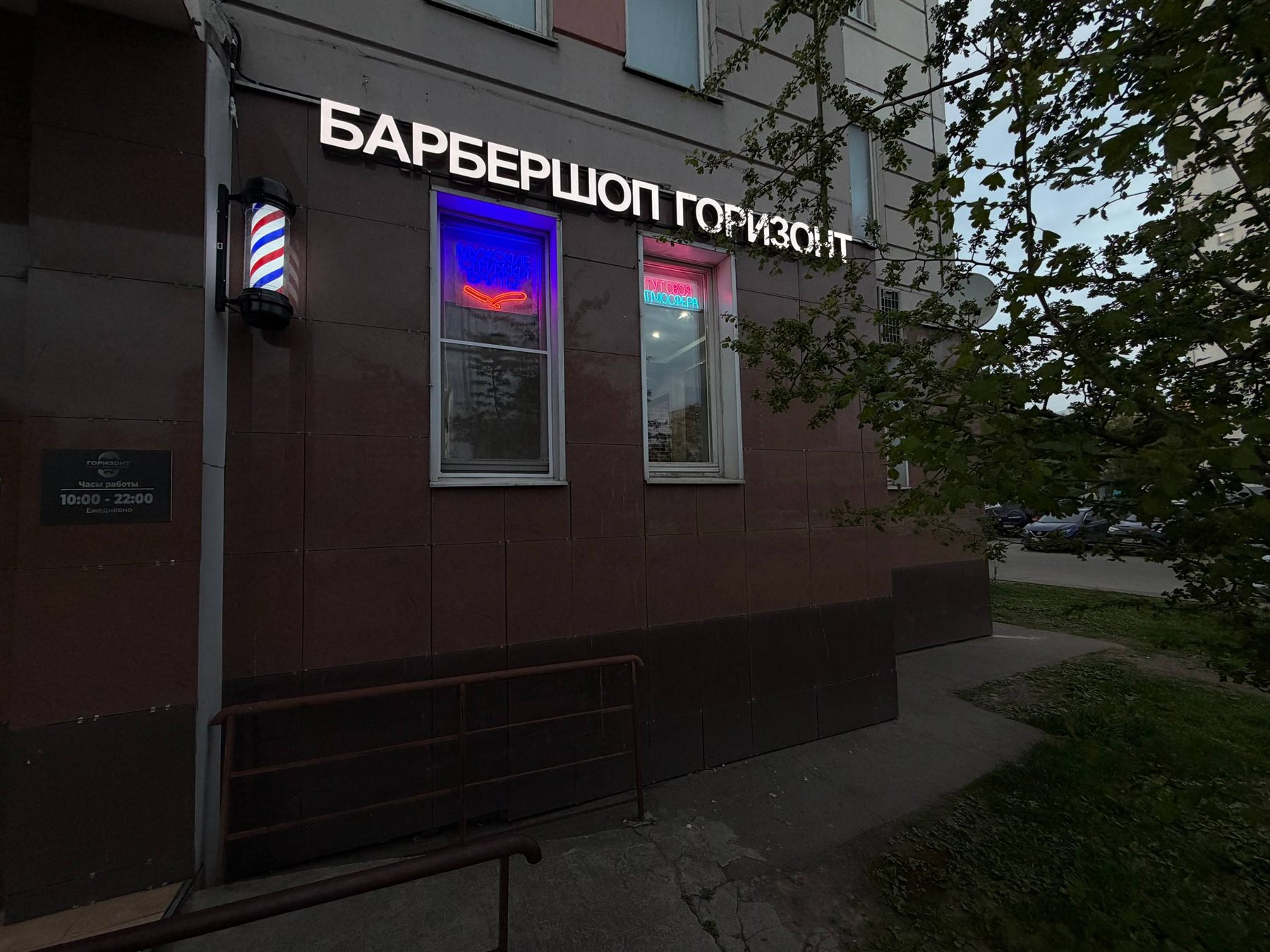Вечерний фасад и светящаяся вывеска барбершопа Горизонт
